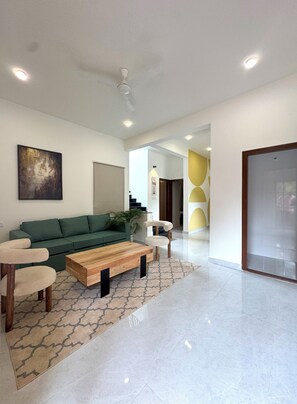 A modern living room with a green sofa, a wooden coffee table, and a patterned rug.