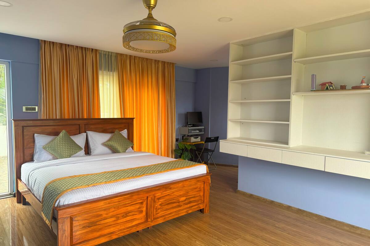 A bedroom with a wooden bed, a ceiling fan, a TV, and a shelf unit.
