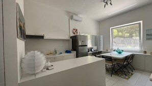 A modern kitchen with white cabinets, a refrigerator, a sink, and a dining area with a table and chairs.