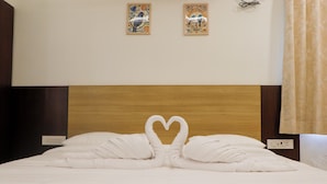 A hotel room with a neatly made bed, two wall-mounted artworks, and a wooden headboard.