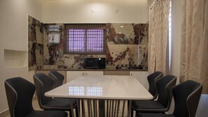 A dining area with a white table and black chairs, a microwave, and a water dispenser on the wall.