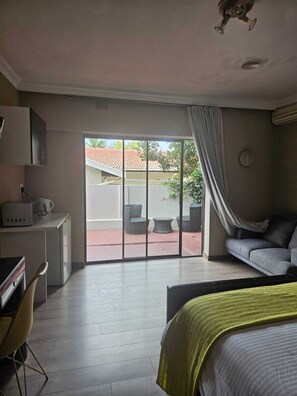 Habitación de hotel con cama, escritorio, computadora, silla y vista al exterior.