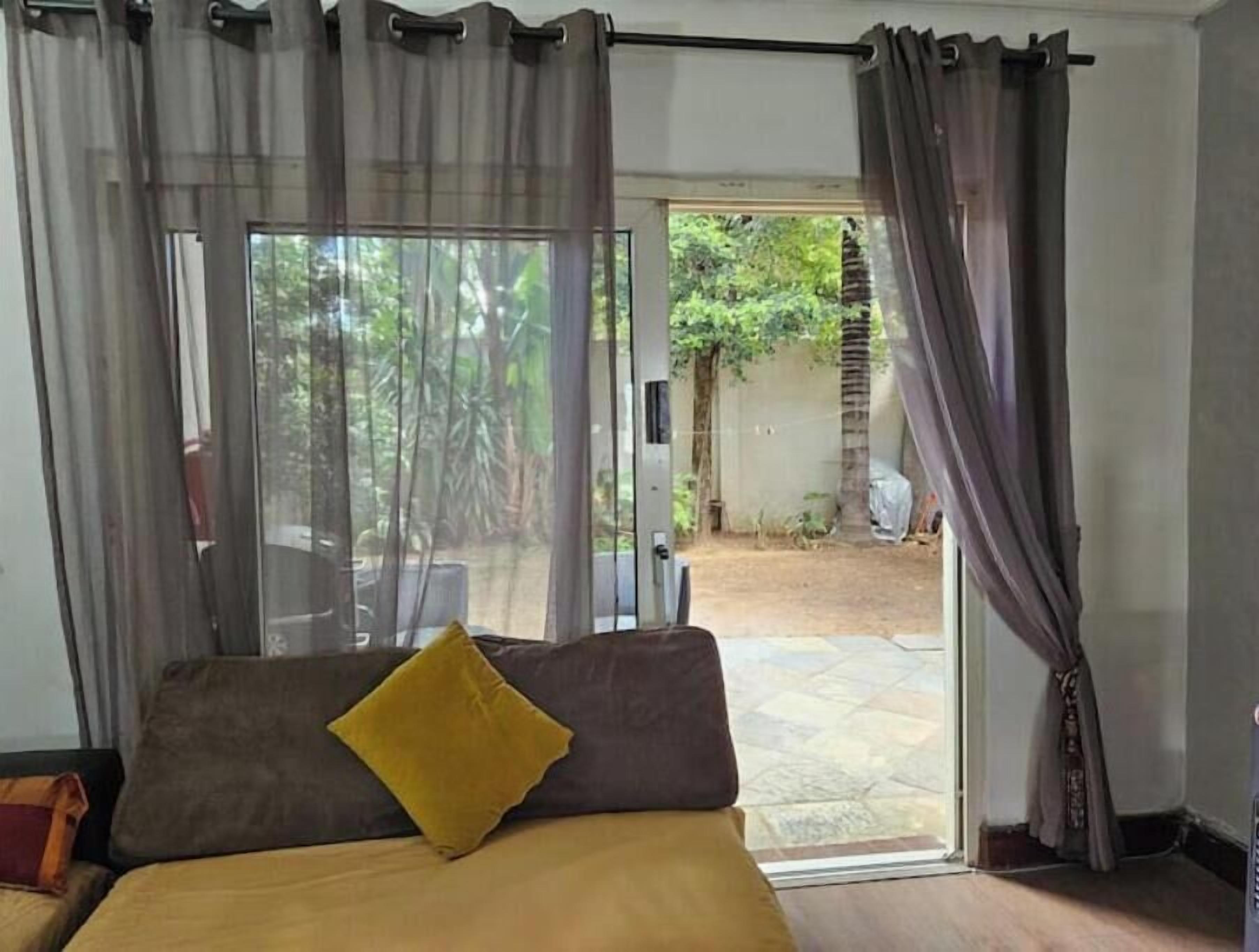 Ein Schlafzimmer mit Bett, einem Fenster mit Vorhängen und Blick auf einen Garten.