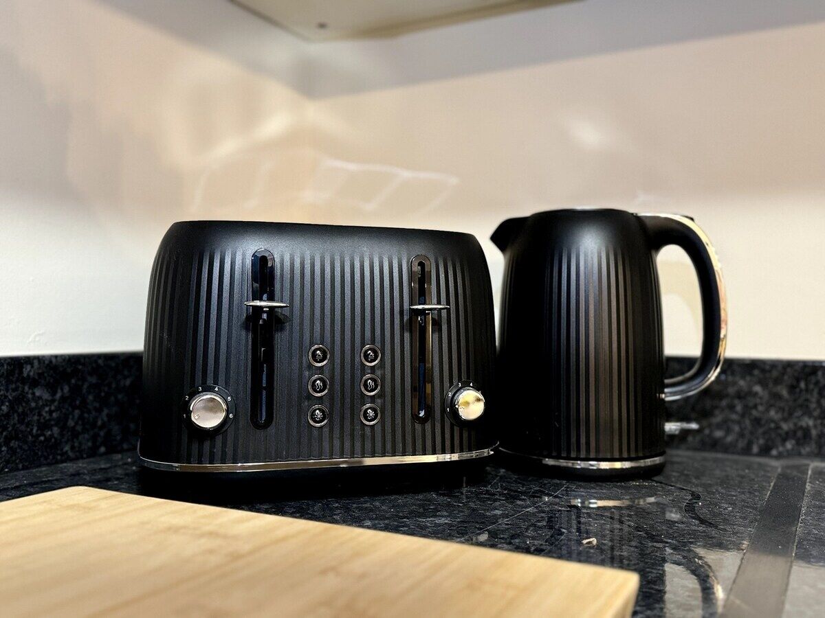 A black toaster and a black mug on a kitchen counter.