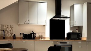 A modern kitchen with white cabinets, a black stove, and a microwave. - Modern Apartment King Room |Free Parking| Suite 9 (Nottingham)