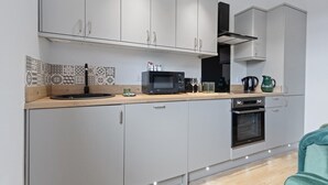Una cocina moderna con armarios grises, microondas, horno y cafetera.