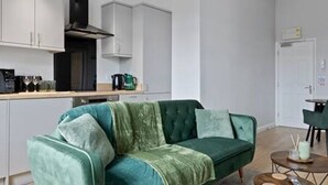 Una sala de estar moderna con un sofá verde, una mesa de centro y un comedor con sillas.