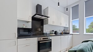 Una cocina moderna con gabinetes blancos, un microondas negro, un horno y un ventanal que proporciona luz natural.