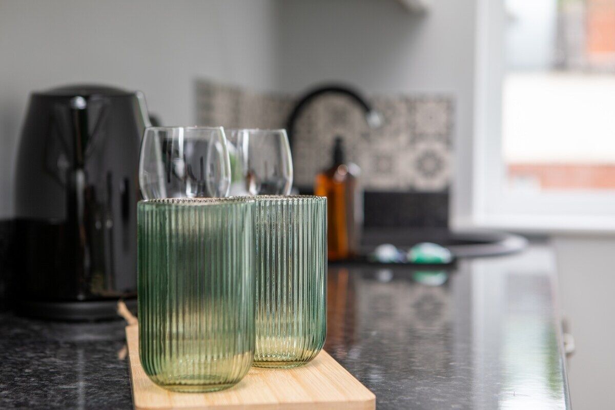 Deux verres transparents sont posés sur une planche en bois, sur le plan de travail de la cuisine.