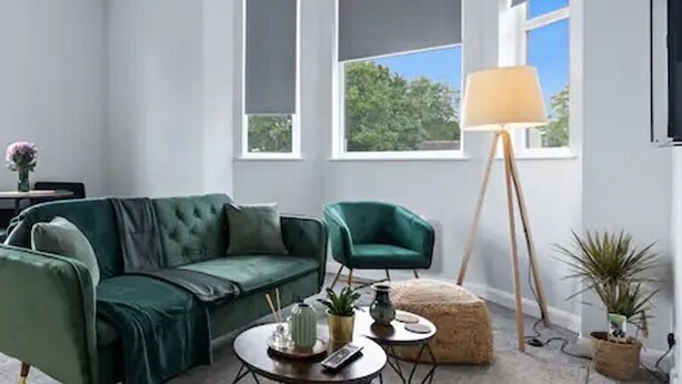 Un salon moderne avec un canapé vert, une petite table ronde et un lampadaire.