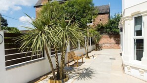 A courtyard with a white building, a bench, and palm trees. - Modern Apartment Double Bed |Free Parking| Suite 4 (Nottingham)
