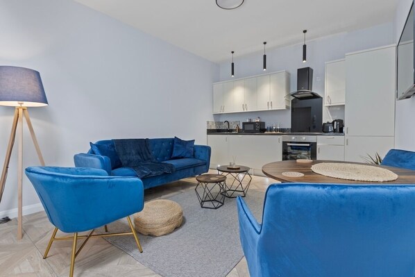 Een moderne woonkamer met een blauwe bank, een bijzettafeltje en een lamp.
