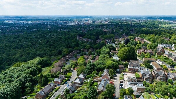 An aerial view of a residential area with houses, roads, and surrounding greenery.