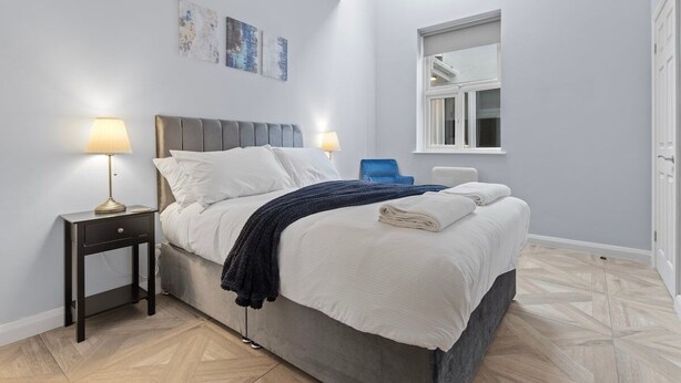 A bedroom with a bed, bedside tables, a window, and artwork on the wall. - Modern Apartment Double Bed |Free Parking| Suite 4 (Nottingham)