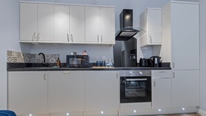A modern kitchen with white cabinets, a black stove, and a patterned backsplash. - Modern Apartment Double Bed |Free Parking| Suite 4 (Nottingham)