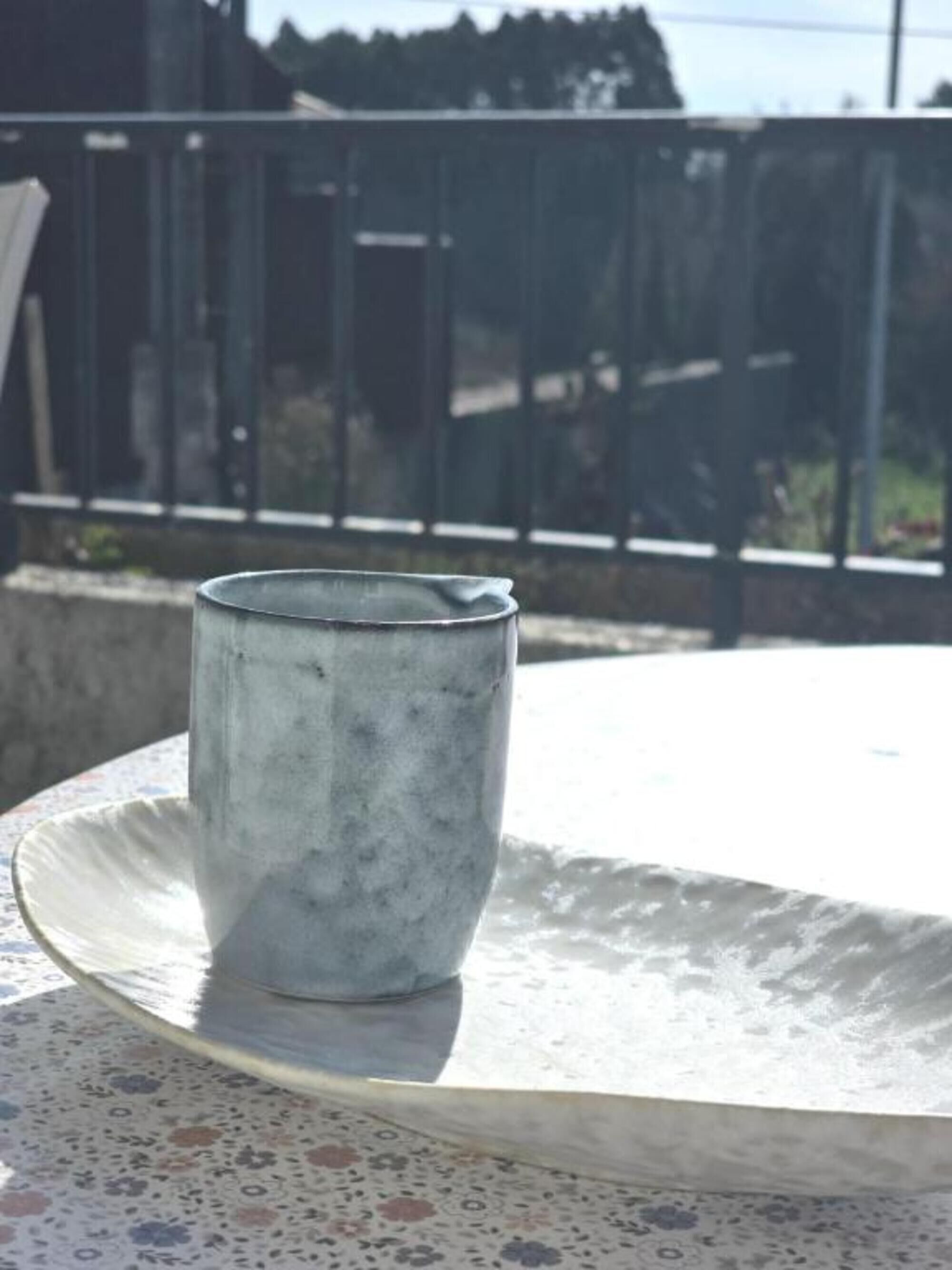 Une tasse en métal posée sur une table à motifs, à l’extérieur.