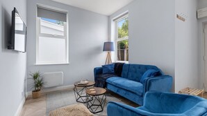Una sala de estar moderna con un sofá azul, dos sillones a juego, una mesita de centro y una lámpara de pie.