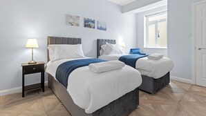 Una habitación de hotel con dos camas, una mesita de noche con lámpara y una obra de arte en la pared.