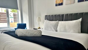 A modern hotel room with a large bed, a nightstand, a lamp, and a view of the outside. - Modern Apartment |King Bed |Free Parking Suite 2 (Nottingham)