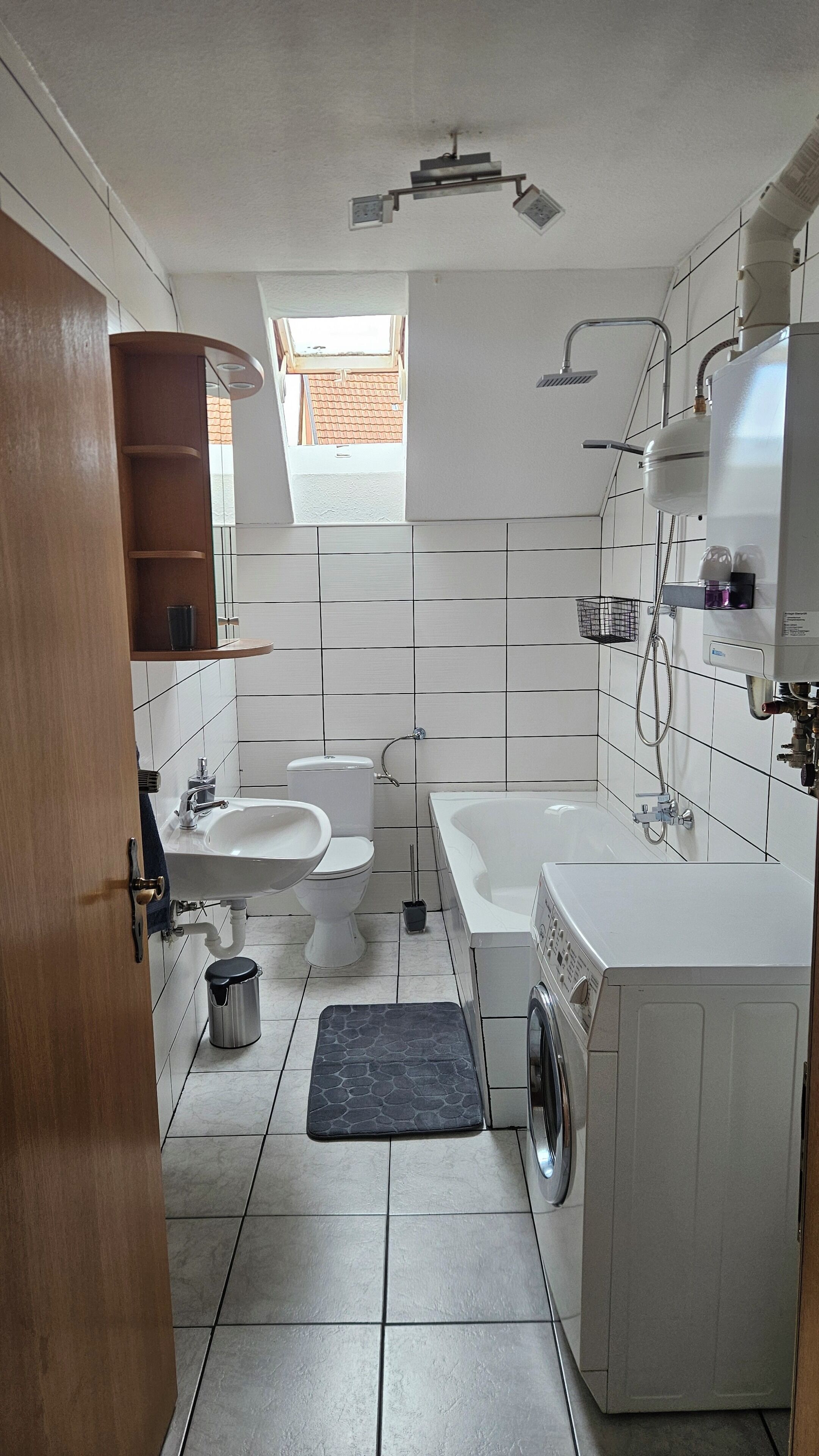 A modern bathroom with a sink, toilet, bathtub, and washing machine.