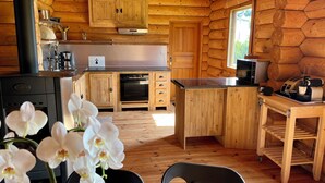 A cabin-style kitchen with wooden walls, a central island, and a stove. - Datcha at Cap Fréhel (Plévenon)