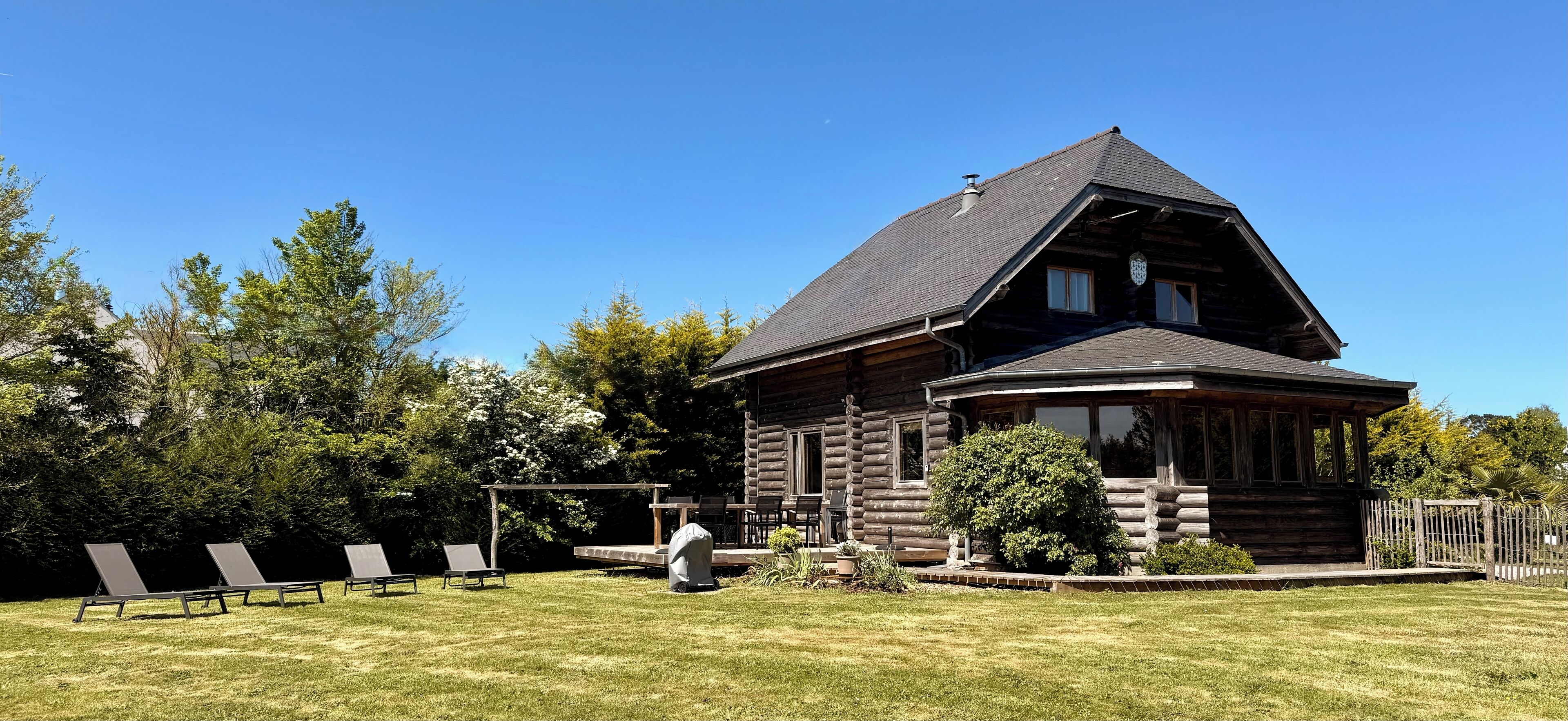 Une cabane en rondins avec un toit en pente, une véranda et une petite terrasse.