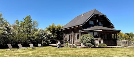 A log cabin with a sloped roof, a porch, and a small deck.