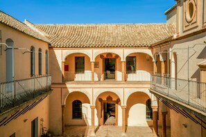 A courtyard with a tiled roof, arches, and a balcony. - Palacio Catalina - Ten Bedroom Villa, Sleeps 22 (Lora del Río)