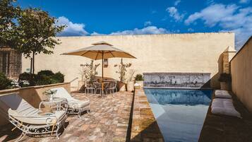 A poolside area with lounge chairs, a table, and an umbrella.