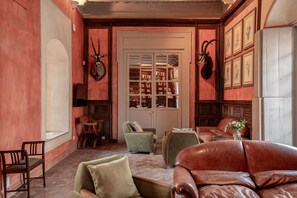 A room with a fireplace, leather sofas, a bookshelf, and framed pictures on the wall.