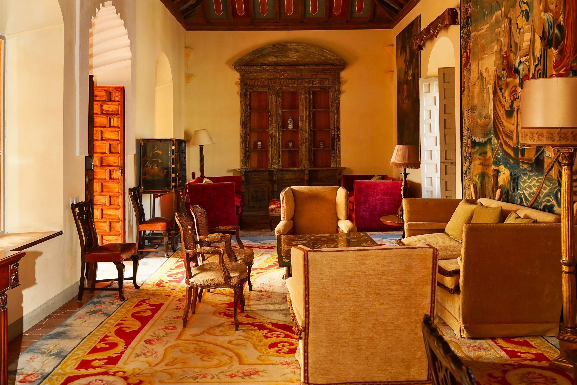A traditional room with a fireplace, seating area, and a large painting on the wall.