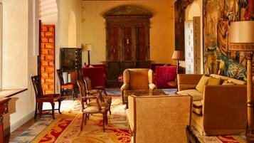 A traditional room with a fireplace, seating area, and a large painting on the wall.