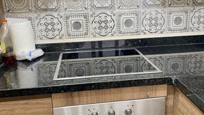 A kitchen with a stainless steel range hood, a black countertop, and a patterned backsplash. - Superb Colina Smir apartment, swimming pool view in front of magnificent Kabila Beach (Marina Smir)