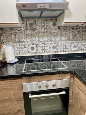 A kitchen with a stainless steel range hood, a black countertop, and a patterned backsplash. - Superb Colina Smir apartment, swimming pool view in front of magnificent Kabila Beach (Marina Smir)