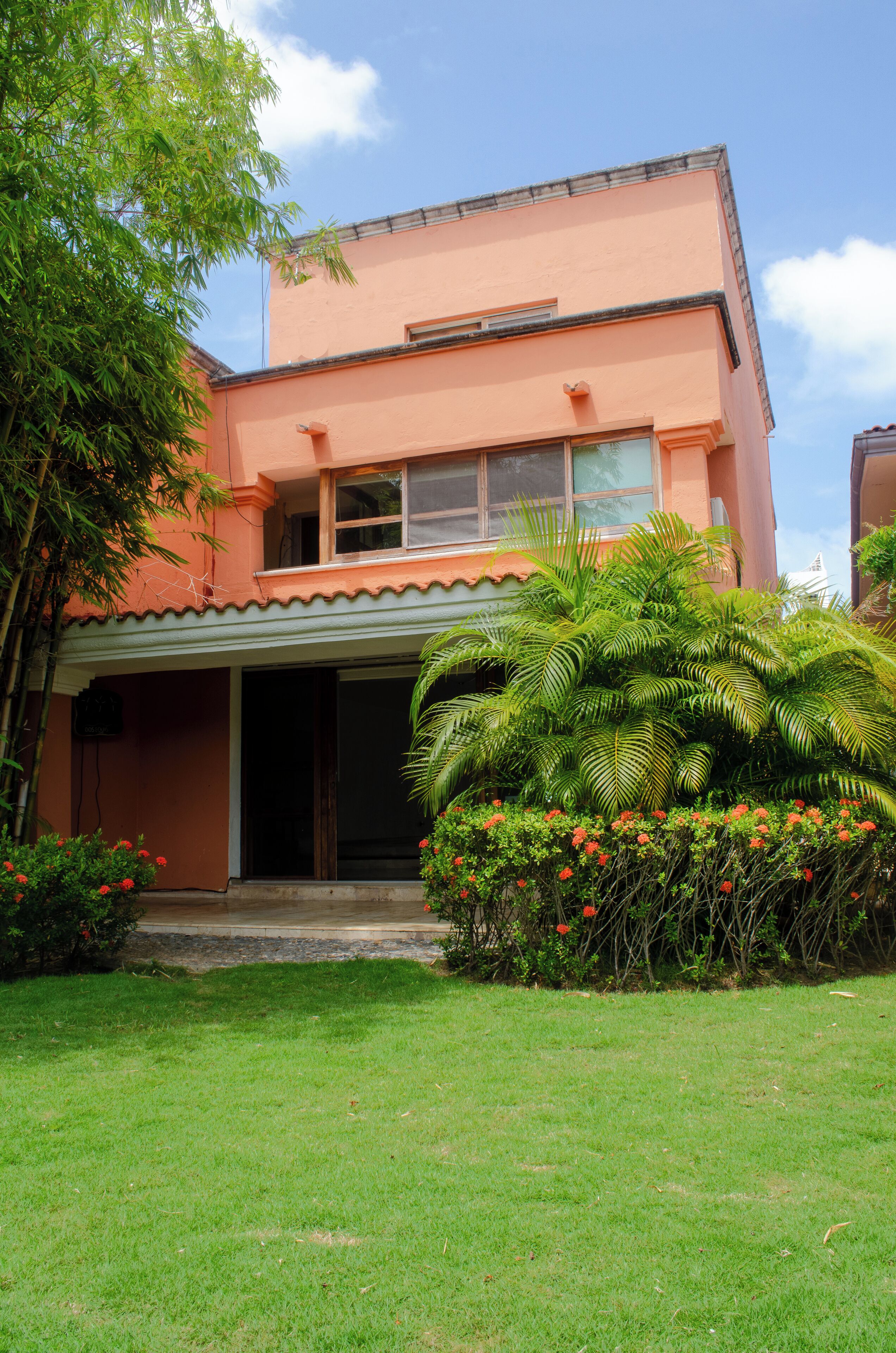 A two-story building with a flat roof, a balcony on the upper floor, and a covered entrance.