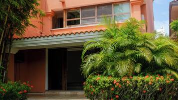 A two-story building with a flat roof, a balcony on the upper floor, and a covered entrance.