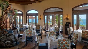 Un comedor con mesas dispuestas para los invitados, con sillas estampadas y una estatua a la izquierda.
