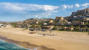 Un complejo turístico frente al mar con villas privadas en la playa, una playa arenosa y vistas al océano.