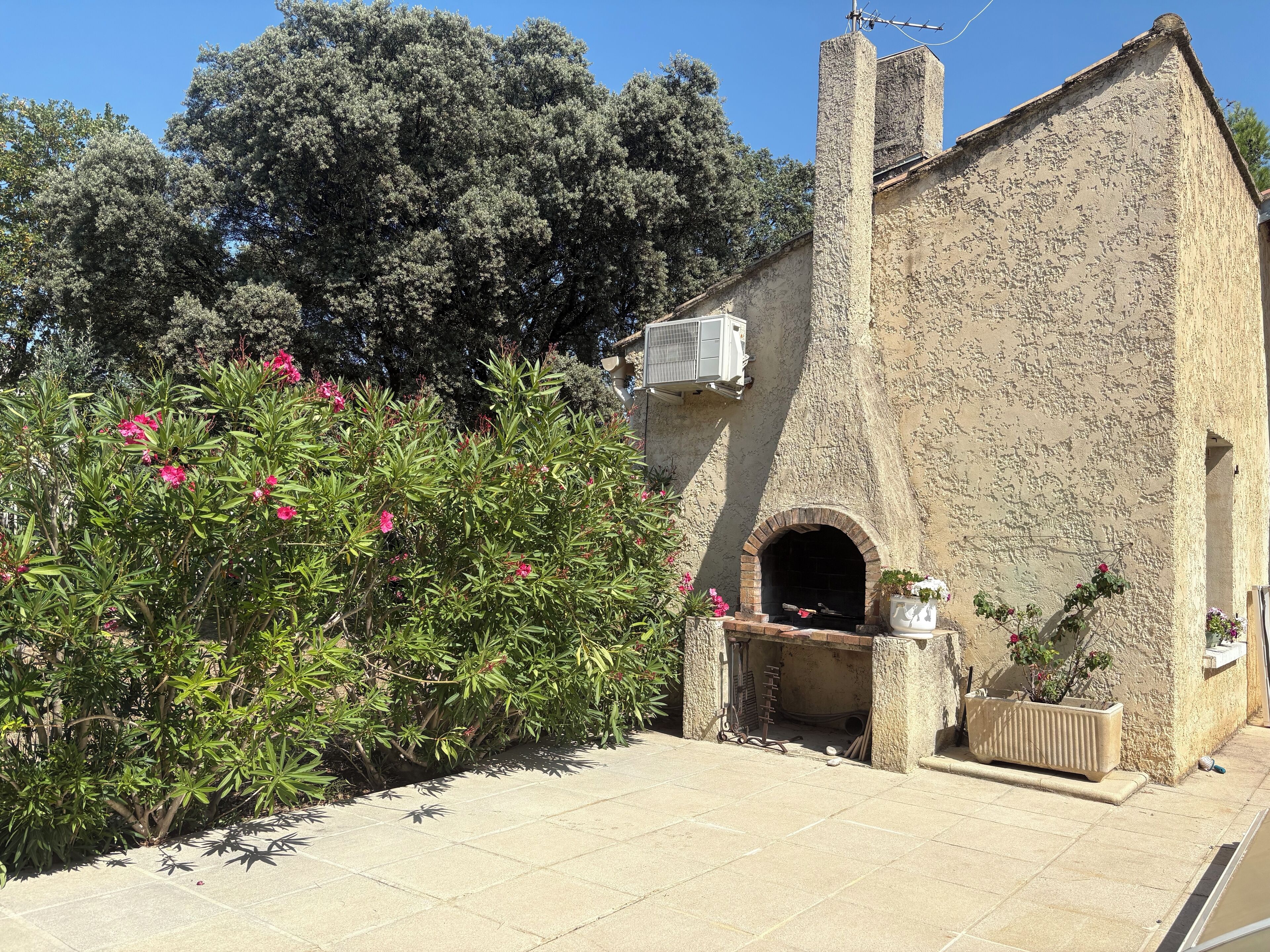 A stone building with a brick oven, surrounded by greenery and trees.