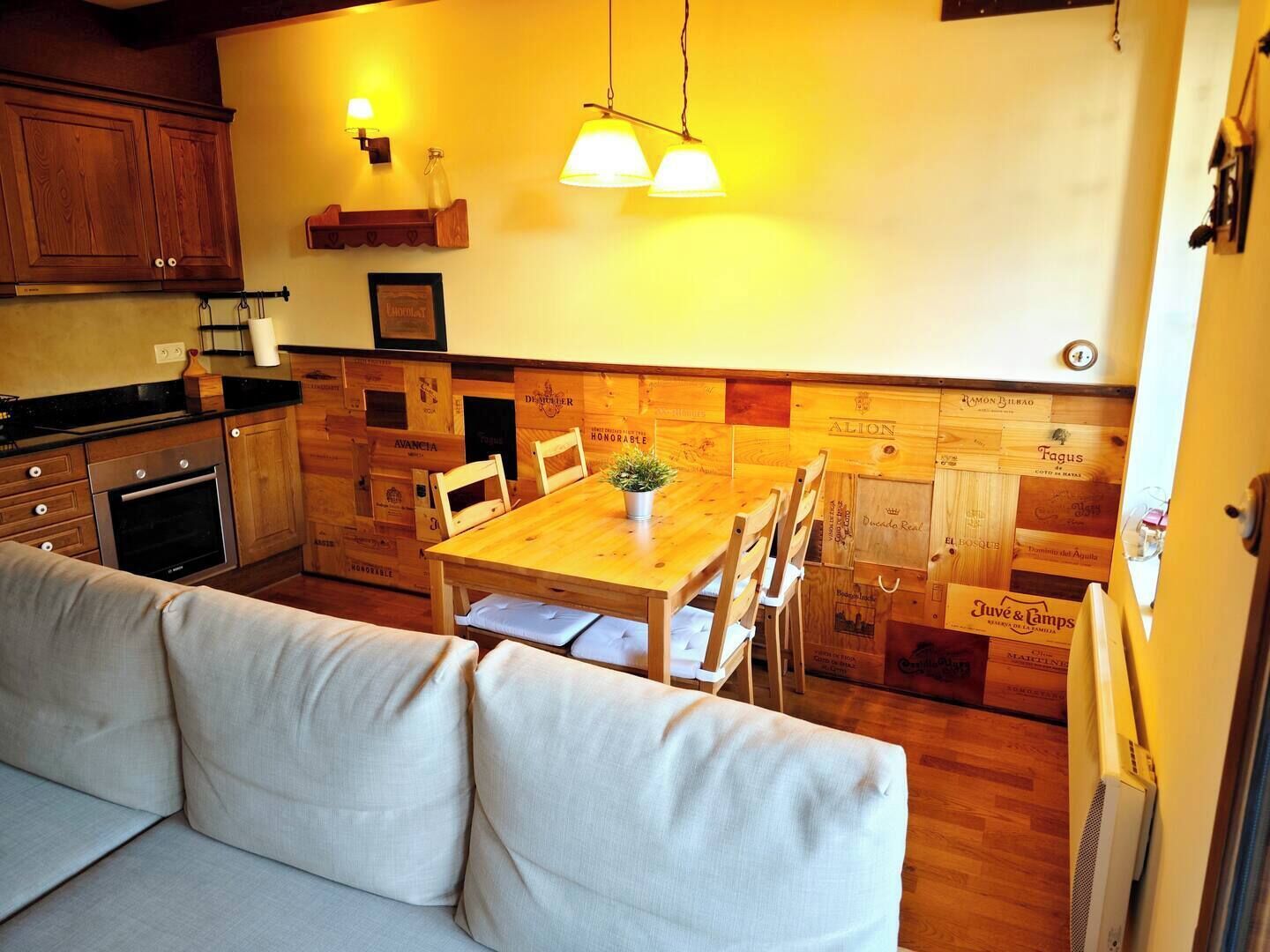 Une cuisine chaleureuse avec des meubles en bois, une table à manger avec des chaises et un canapé.