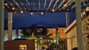 Un balcon agrémenté de guirlandes lumineuses, une petite table et des chaises.
