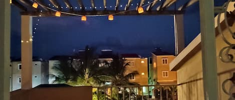 A balcony with string lights, a small table, and chairs.