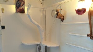 Un baño con paredes blancas, un radiador, un reloj y una estantería con un objeto decorativo.