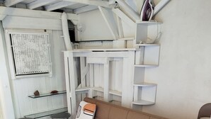 Una sala de estar con un sofá beige, una mesita y una pared blanca con estanterías.