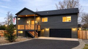 Ein zweistöckiges Haus mit überdachter Veranda, Garage und gepflegter Auffahrt.