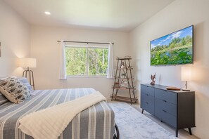 Une chambre à coucher avec un lit, une commode, une échelle, une fenêtre et un tableau.