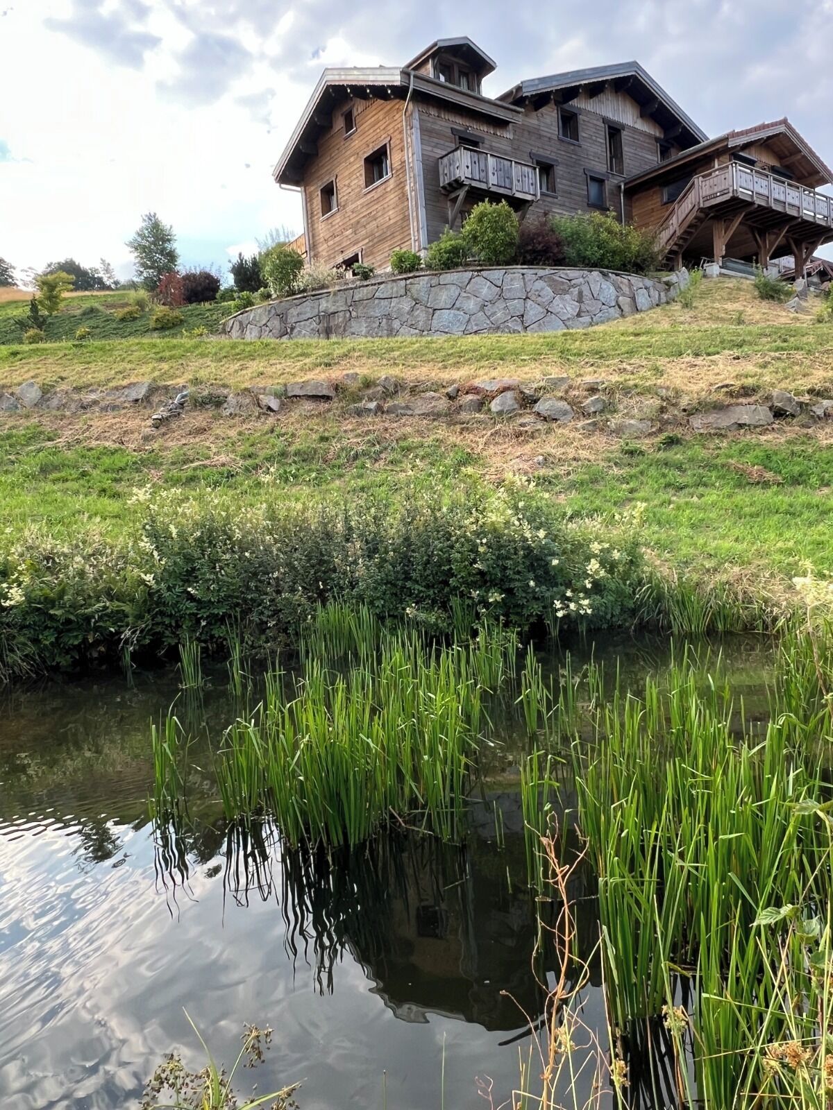 Ett rustikt trähus med en grund av sten, en stenmur och en träveranda.