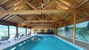 Una amplia piscina cubierta con techo de madera y un mural de un bosque en la pared.