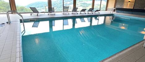 Una piscina con sillas de descanso y vistas a las montañas.