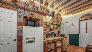 A rustic kitchen with wooden accents, a white refrigerator, and vintage-style cabinets labeled with produce names.
